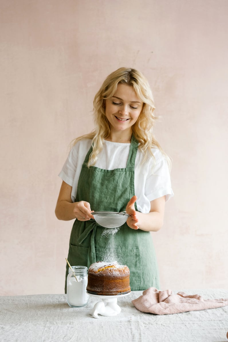 Woman Sprinkling Confectioner's Sugar on Baked Cake